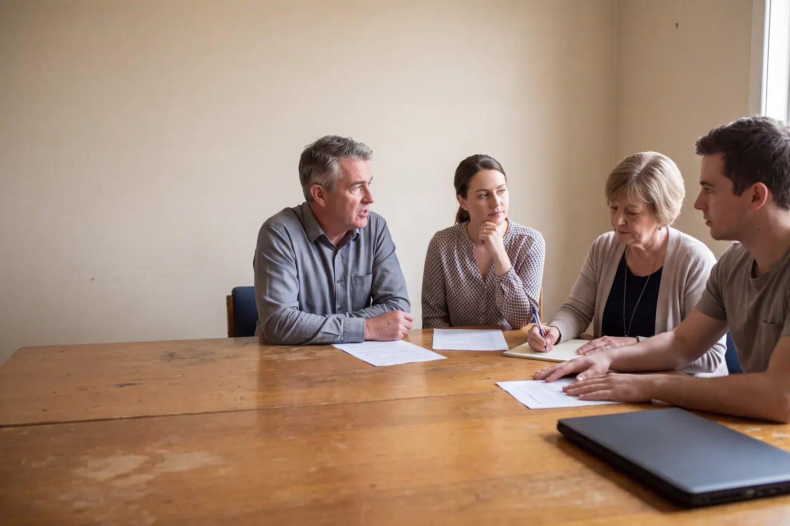 Four colleagues of different ages working through printed pages together around a meeting table