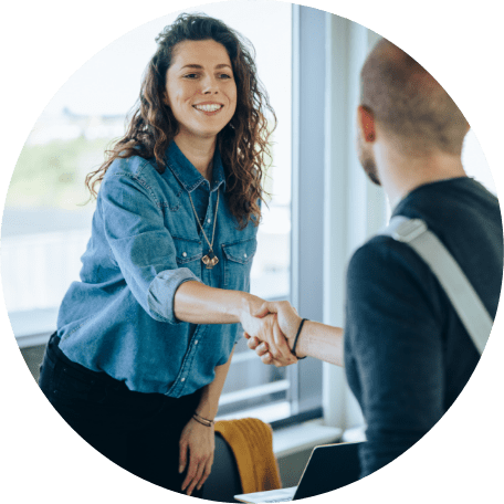 A female hiring manager is shaking hands with the best matched candidate for an open role in her business.