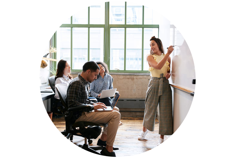 A group of people in a room conducting psychometric assessments for candidate hiring and discussing business culture dynamics on a whiteboard.